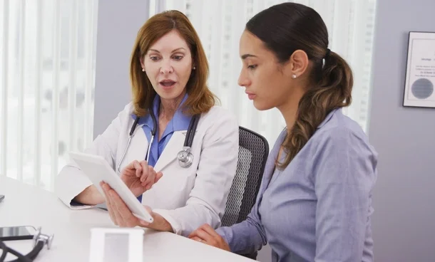 Senior doctor using tablet to share results of patients health condition