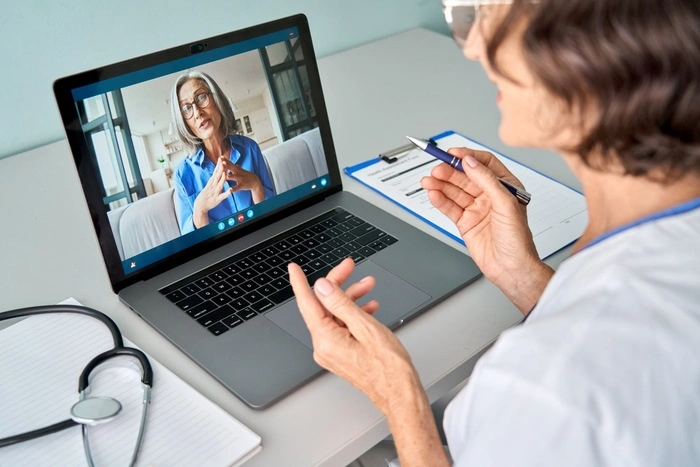 Female doctor therapist consulting older senior patient via virtual video call visit using laptop computer