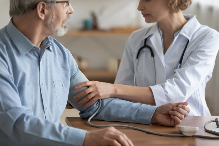 Close up skilled young female family doctor gp physician measuring blood pleasure of mature middle aged male patient at checkup meeting