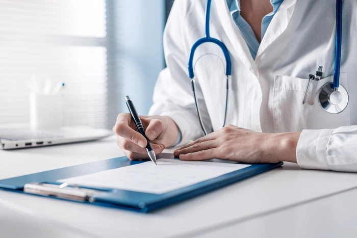 Doctor sitting at desk and writing a prescription for her patient