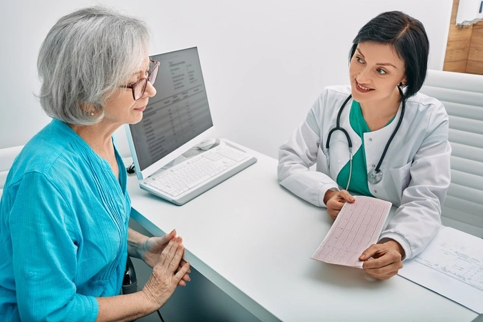 Positive doctor consulting senior woman on results of cardiogram and test.